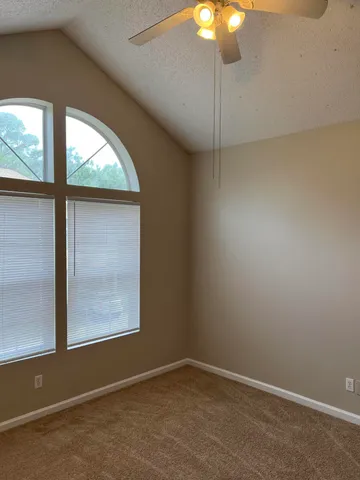 an empty room with windows and fan