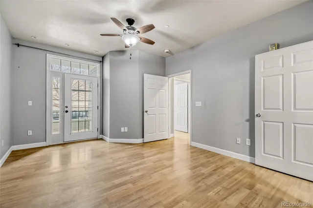 a view of an empty room with chandelier fan and wooden floor