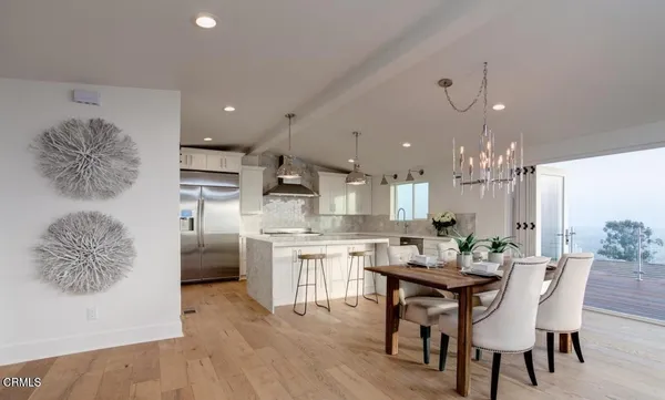 a kitchen with stainless steel appliances kitchen island granite countertop a dining table chairs sink and cabinets