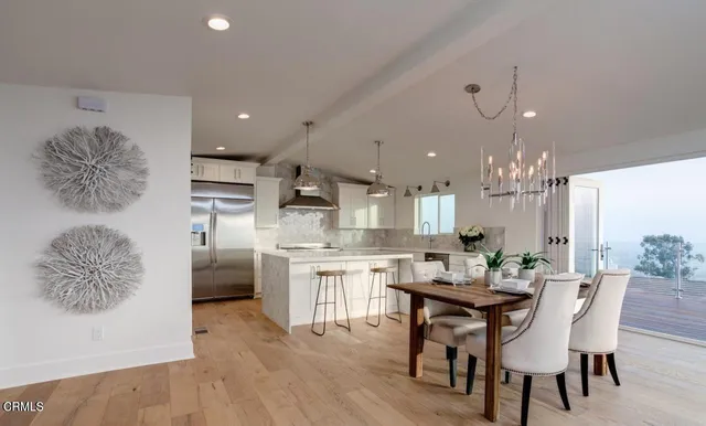 a kitchen with stainless steel appliances kitchen island granite countertop a dining table chairs sink and cabinets