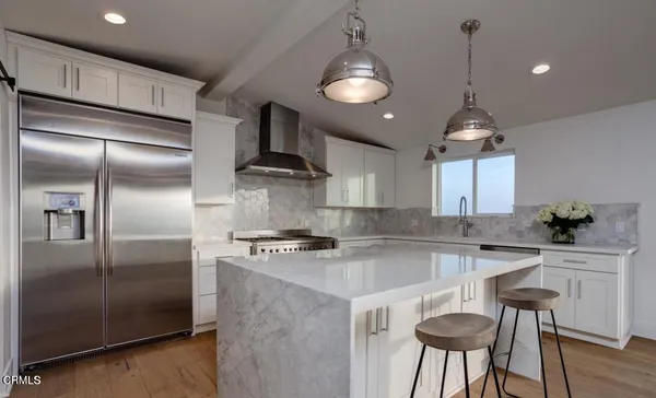 a kitchen with kitchen island a counter space a refrigerator and cabinets