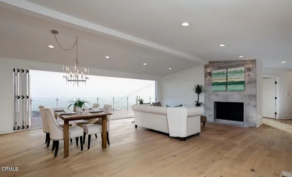 a living room with furniture a fireplace and a dining table with kitchen view