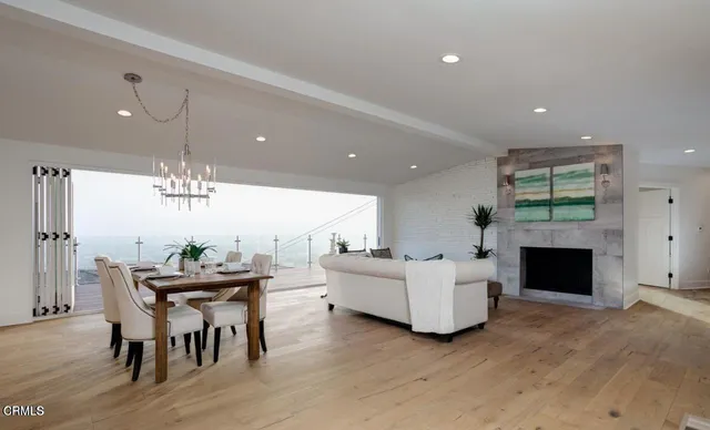 a living room with furniture a fireplace and a dining table with kitchen view