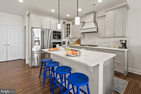 a kitchen with stainless steel appliances a stove a sink a refrigerator cabinets and wooden floor