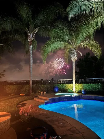 a view of a swimming pool with a table and chairs under palm trees