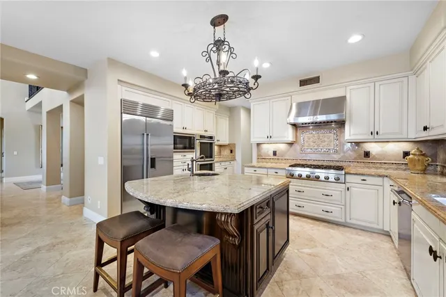 a kitchen with stainless steel appliances granite countertop a sink a stove and a wooden cabinets