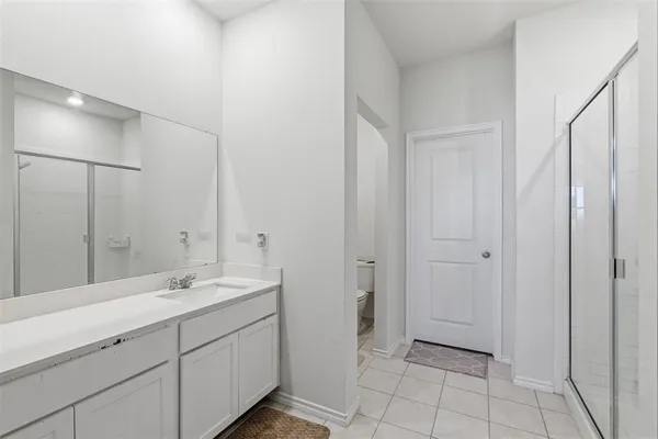 a spacious bathroom with a double vanity sink a mirror and a shower
