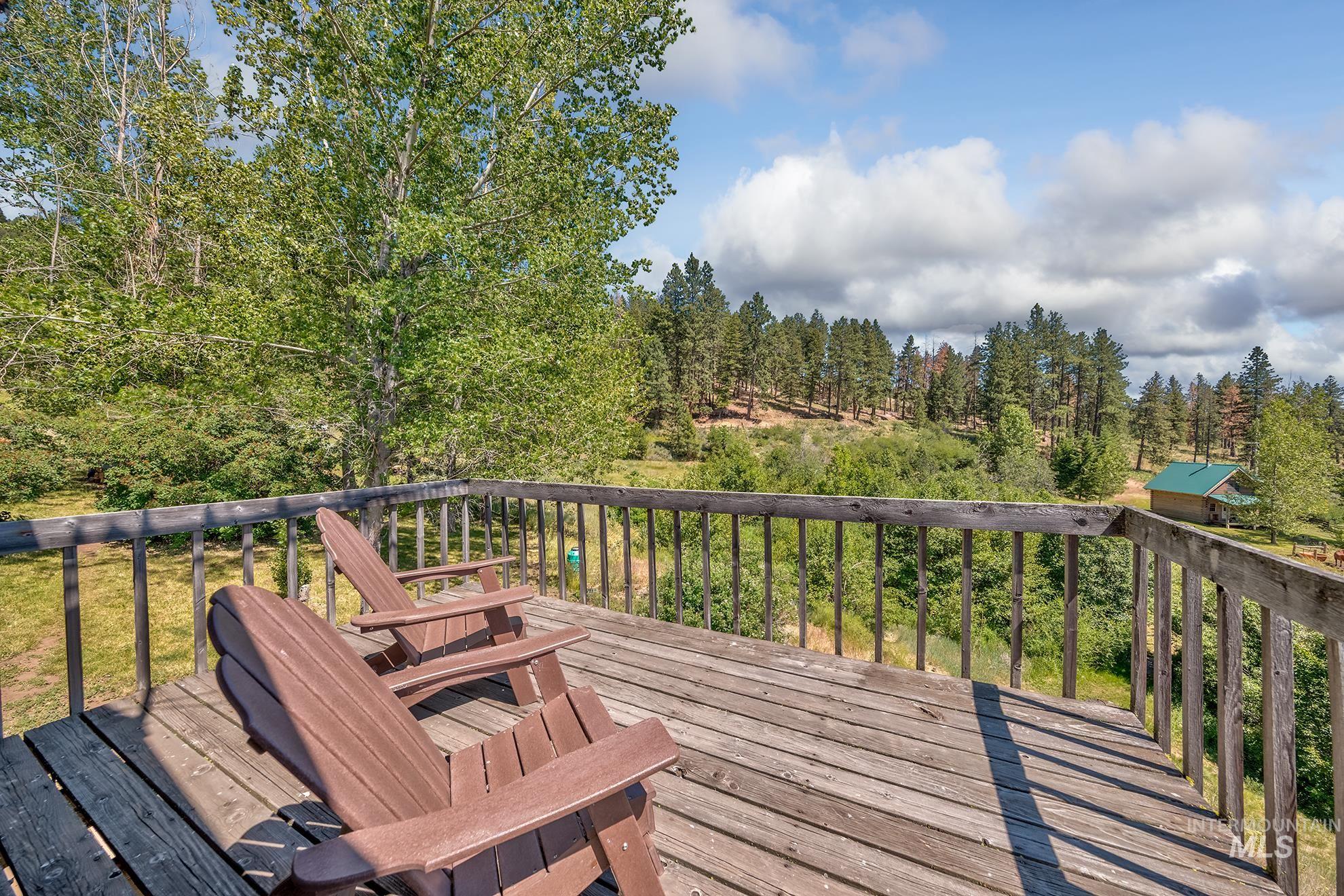 2150 Seid Creek Road Cambridge, ID 83610 - Photo 21 of 50 Expansive outdoor deck with natural wood flooring and railing, overlooking a wooded landscape