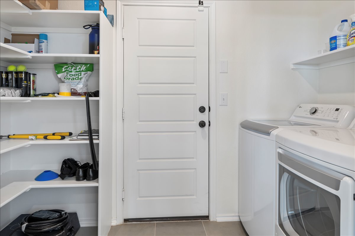 18501 Spotted Eagle Lane Elgin, TX 78621 - Photo 35 of 40 A well-organized utility room features a washer and dryer alongside ample shelving for storage.