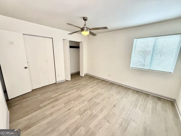 an empty room with wooden floor a ceiling fan and a ceiling fan