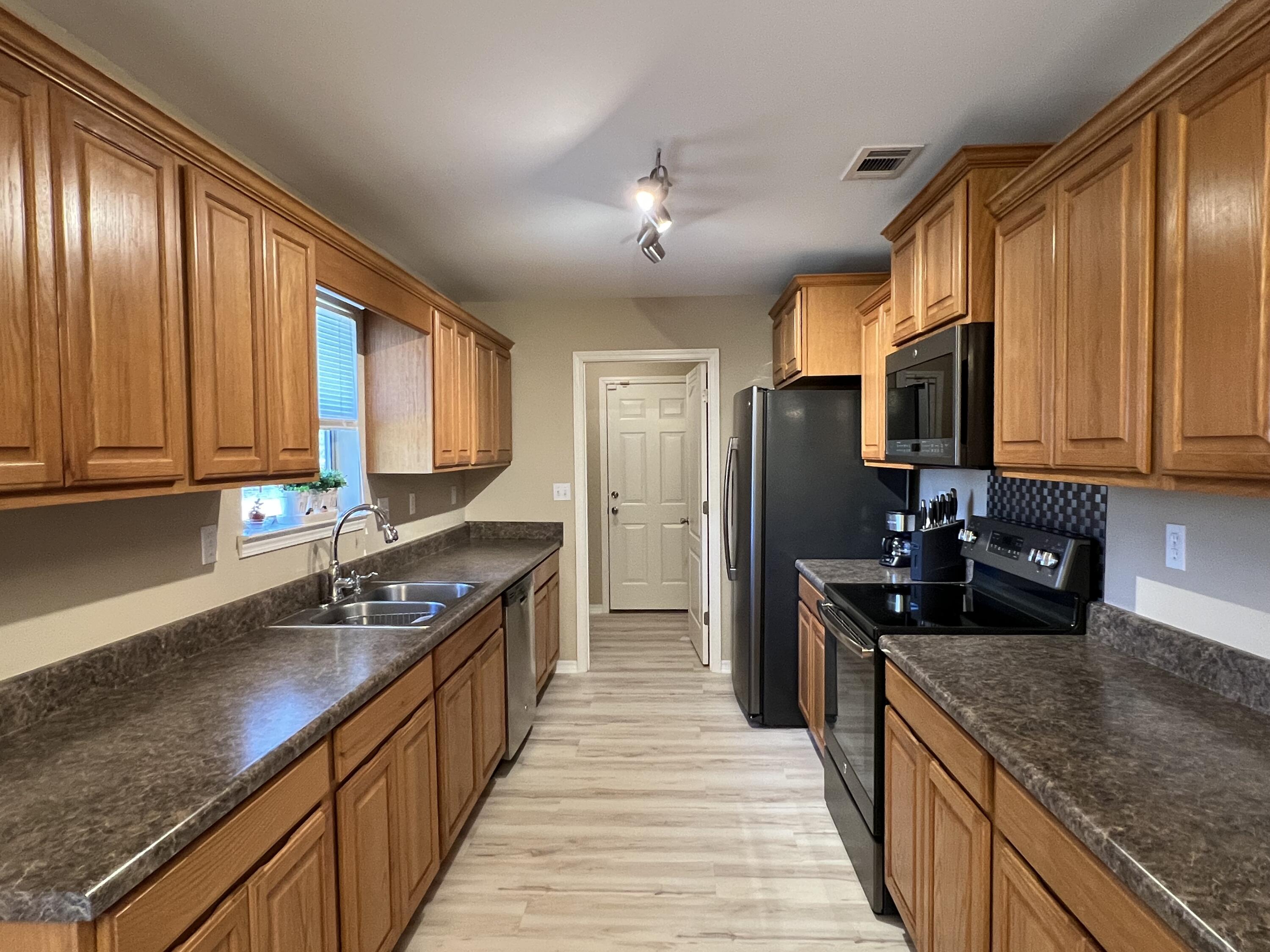 4645 Dove Way Crestview, FL 32539 - Photo 5 of 21 a kitchen with stainless steel appliances granite countertop a stove a sink dishwasher a refrigerator and cabinets with wooden floor