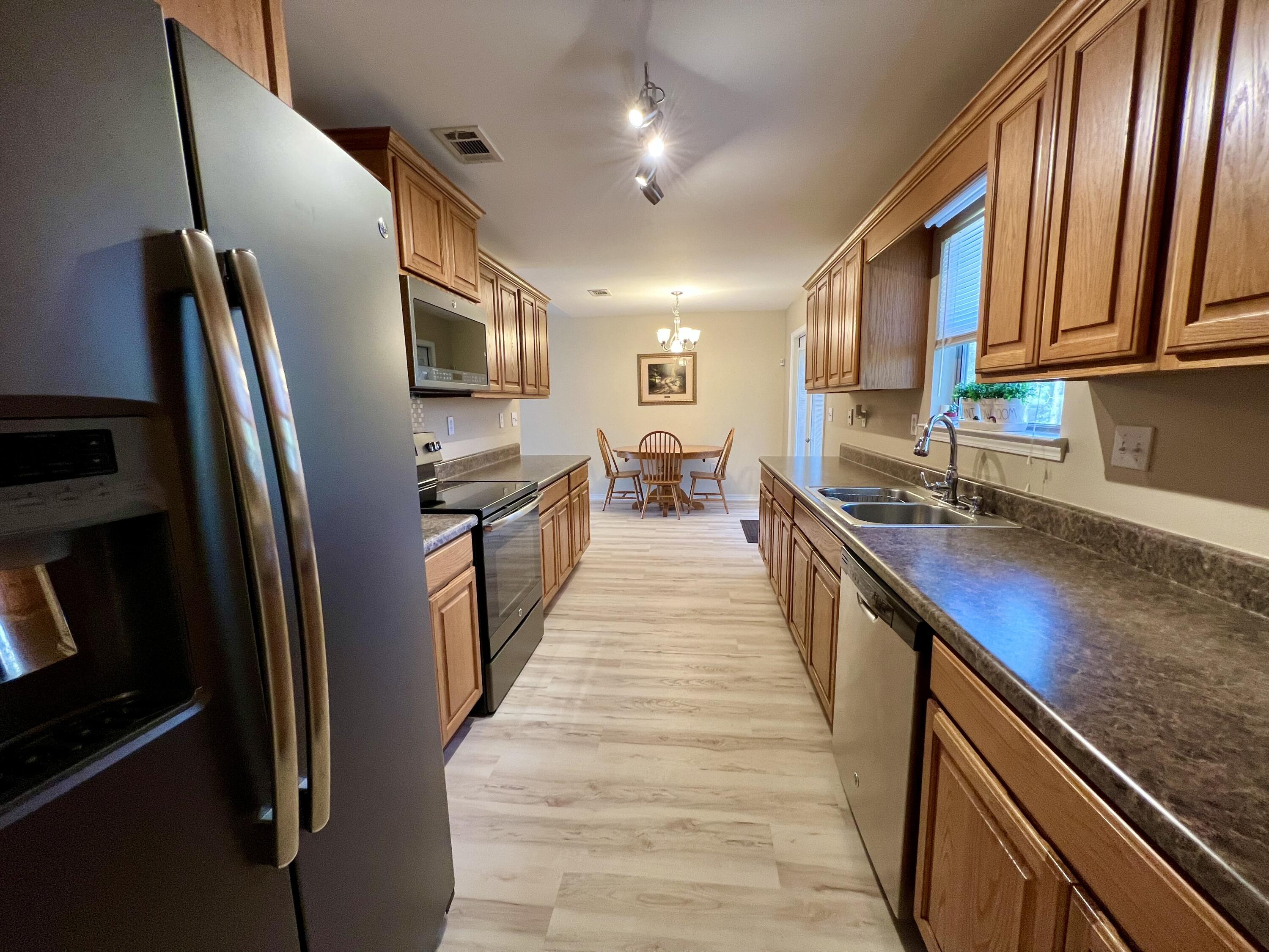 4645 Dove Way Crestview, FL 32539 - Photo 6 of 21 a open kitchen with stainless steel appliances granite countertop a refrigerator a stove and a sink with wooden floor