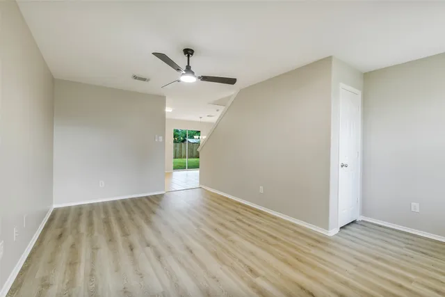 an empty room with wooden floor and a ceiling fan