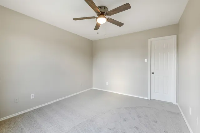an empty room with a ceiling fan and a window