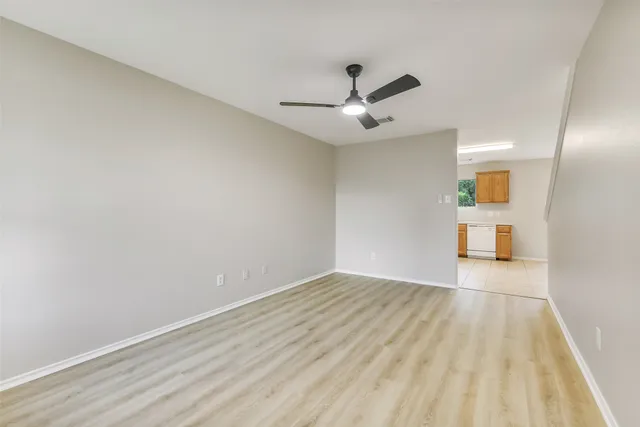 a view of empty room with wooden floor and ceiling fan