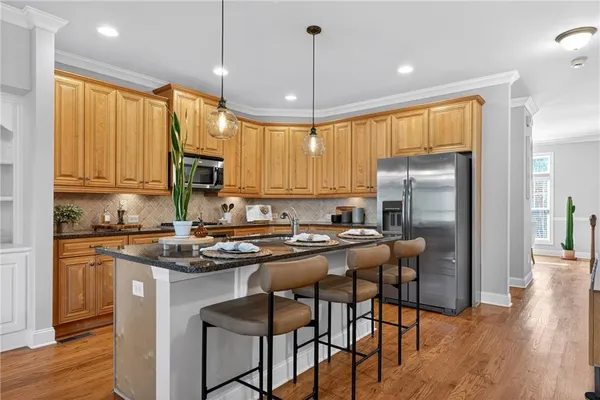 a kitchen with stainless steel appliances granite countertop a stove a refrigerator a sink a stove with white cabinets and wooden floor
