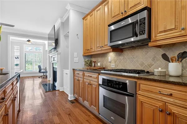 a kitchen with stainless steel appliances a stove a microwave oven cabinets and a wooden floor