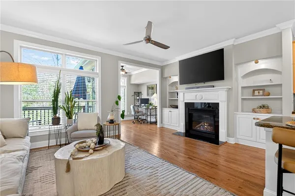 a living room with furniture a fireplace a flat screen tv and a large window