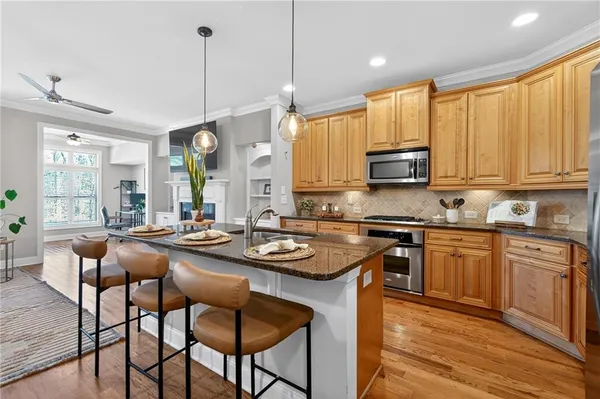 a kitchen with stainless steel appliances granite countertop wooden cabinets a stove a sink a dining table and chairs