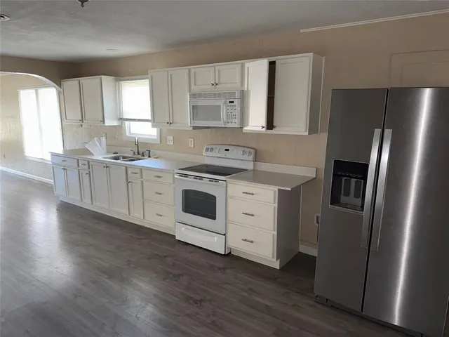 a kitchen with stainless steel appliances white cabinets and wooden floor