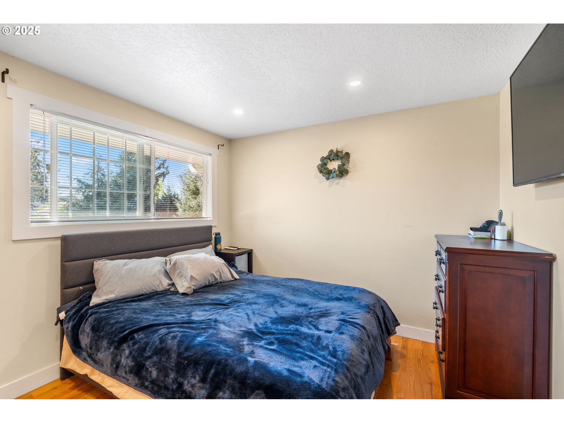 1035 South 11th Street Cottage Grove, OR 97424 - Photo 17 of 30 a bedroom with a large bed and a flat tv screen on dresser
