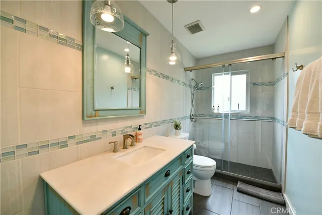 a bathroom with a sink toilet double vanity and shower