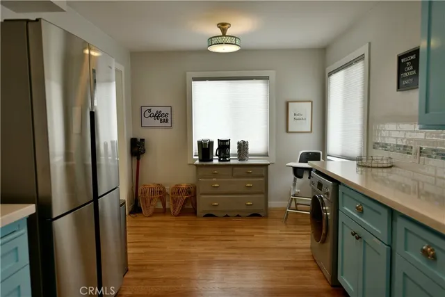 a kitchen with kitchen island a counter top space a sink a refrigerator and a view of living room