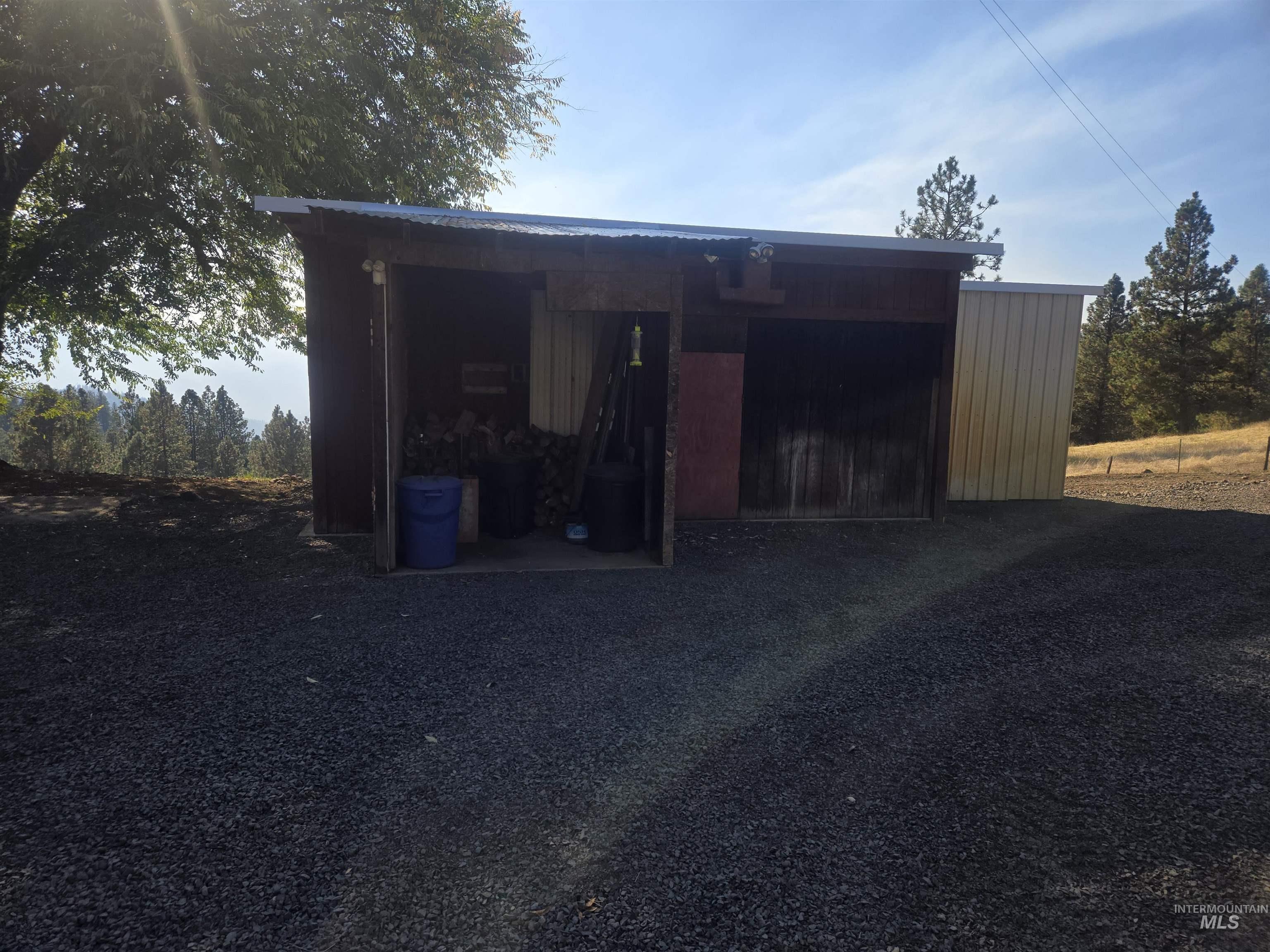 4099 Lakeview Road Orofino, ID 83544 - Photo 15 of 41 Gravel driveway leading to a multi-purpose outbuilding with a metal roof and wood siding