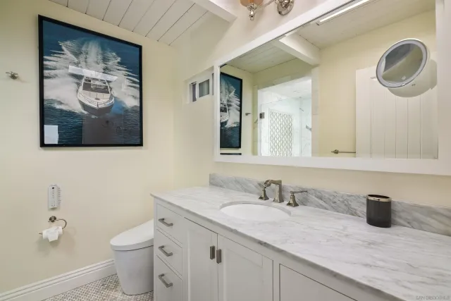 a bathroom with a granite countertop sink mirror vanity and toilet