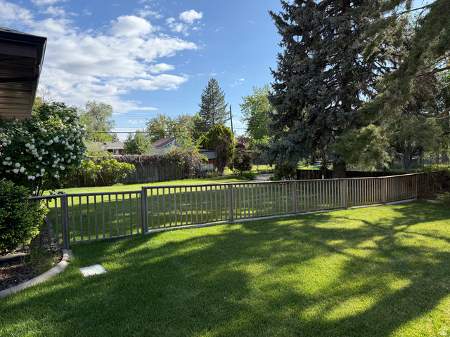 362 East 9150th Street South Sandy, UT 84070 - Photo 18 of 41 Expansive grassy backyard featuring a wooden picket fence, mature trees, and established shrubs