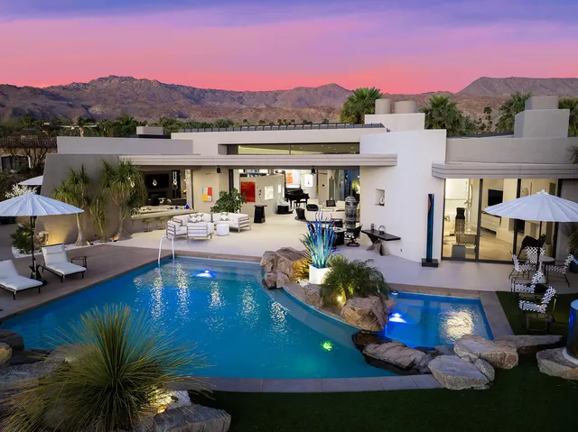 a view of a patio with couches table and chairs potted plants and palm trees