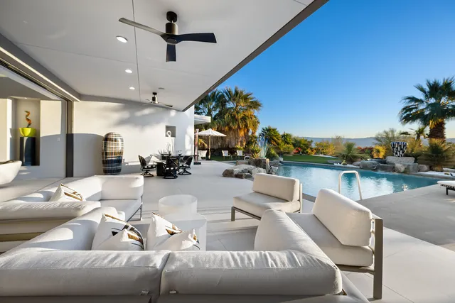 a view of patio with a table and chairs under an umbrella with potted plants