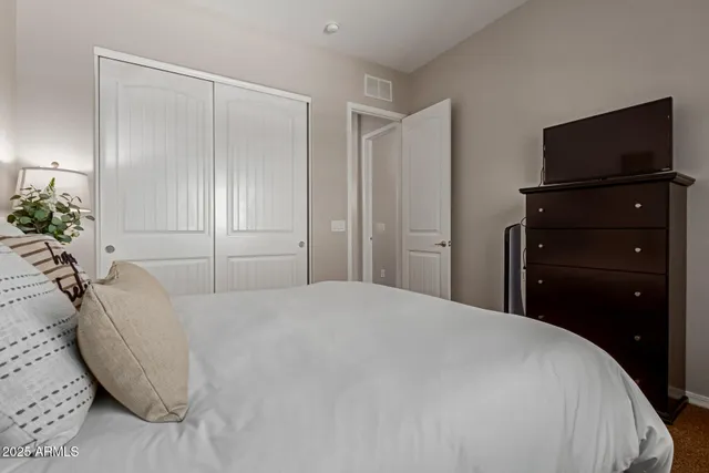 a bedroom with a bed and a flat tv screen on dresser