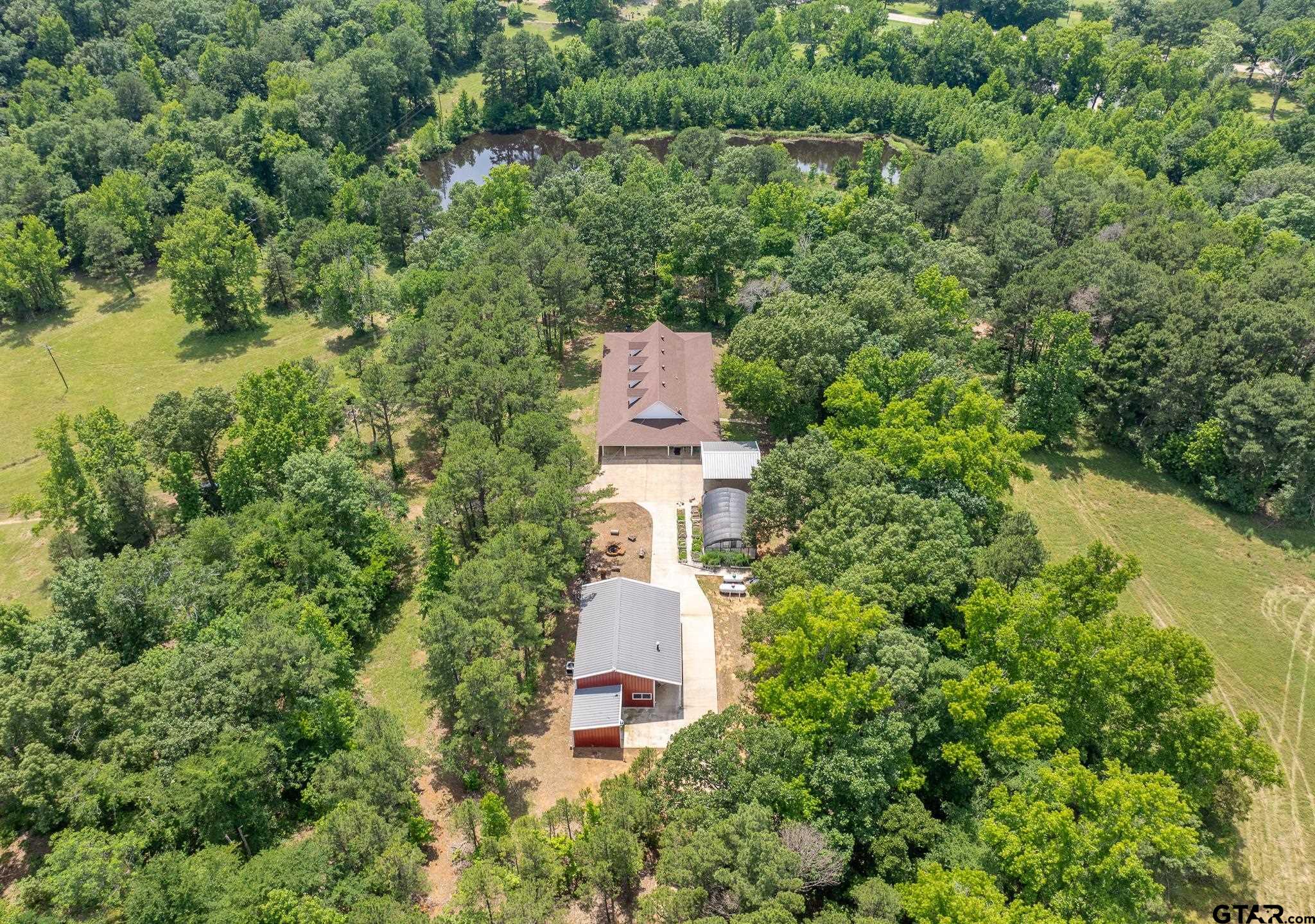an aerial view of a house with a yard and trees in the background