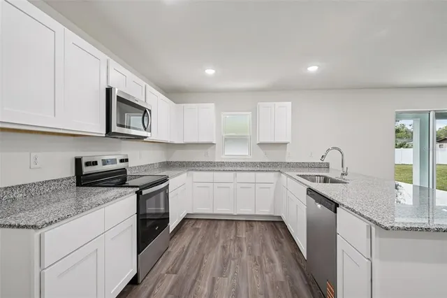 a kitchen with stainless steel appliances granite countertop wooden cabinets granite counter tops and a hard wood floors