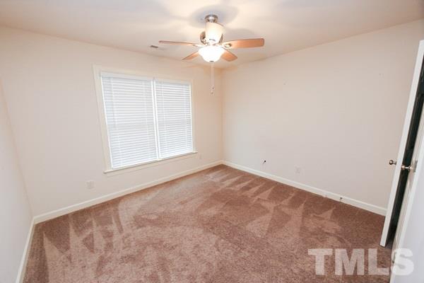 4740 Sandy Bay Circle Raleigh, NC 27603 - Photo 14 of 24 an empty room with a chandelier fan and windows