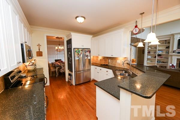 4740 Sandy Bay Circle Raleigh, NC 27603 - Photo 7 of 24 a kitchen with stainless steel appliances granite countertop a sink refrigerator and cabinets