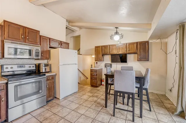 a kitchen with stainless steel appliances a stove a refrigerator and a dining table