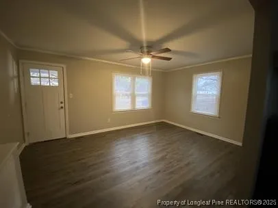 an empty room with wooden floor chandelier fan and windows