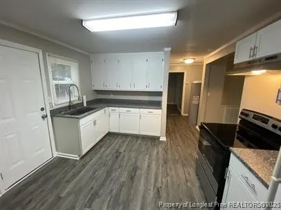 a kitchen with granite countertop a refrigerator stove and wooden floor