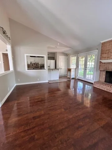 a view of an empty room with window and wooden floor