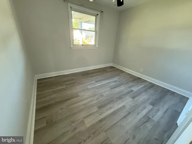 an empty room with wooden floor cabinet and windows