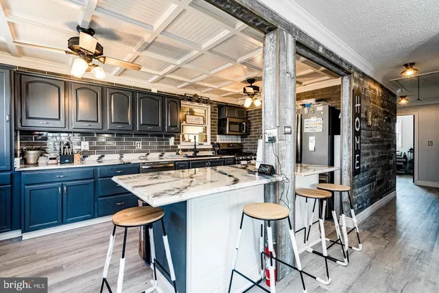 a kitchen with stainless steel appliances kitchen island granite countertop a table chairs sink and cabinets