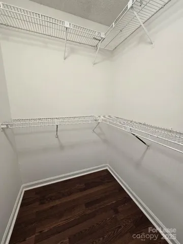 an empty room with wooden floor chandelier fan and windows