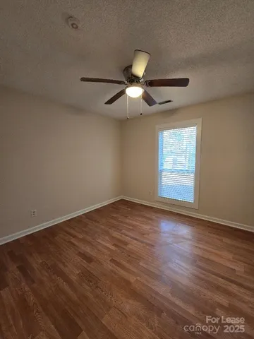 an empty room with wooden floor fan and windows