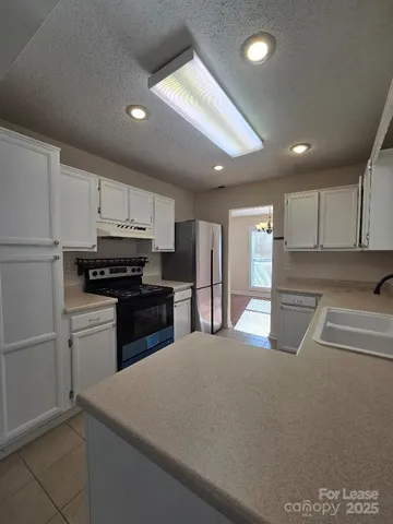 a kitchen with stainless steel appliances granite countertop a refrigerator a stove and a sink