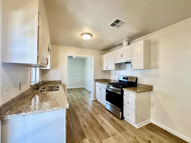 a kitchen with granite countertop a sink a stove and refrigerator