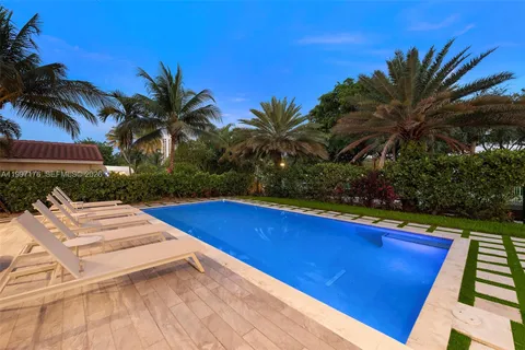 a view of house with swimming pool outdoor seating and trees in the background