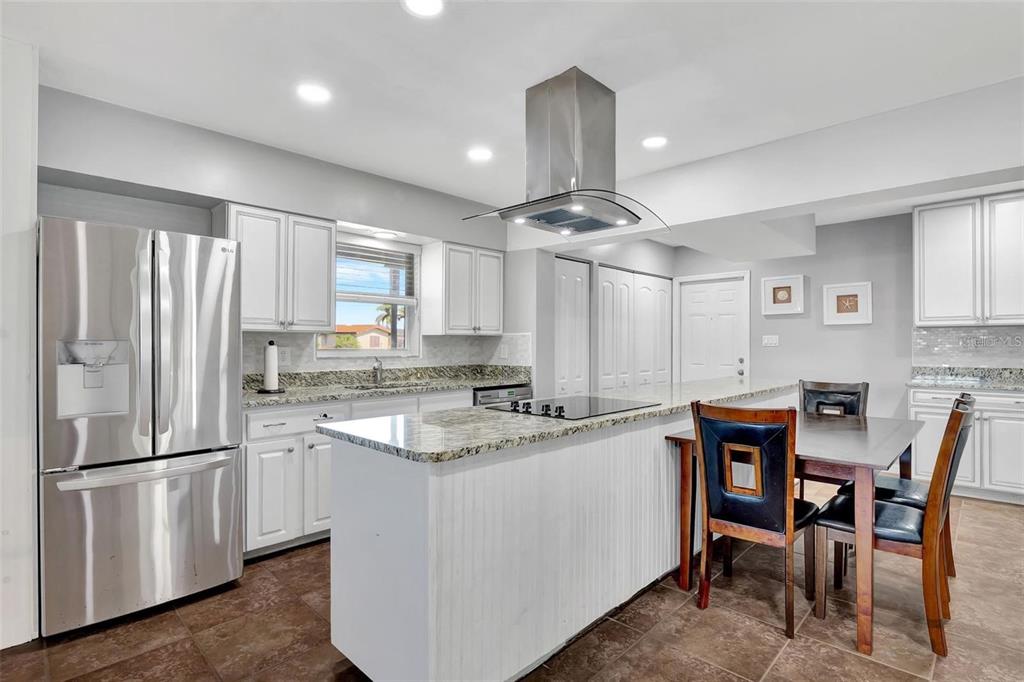 250 Bangsberg Road Southeast Port Charlotte, FL 33952 - Photo 4 of 59 a kitchen with stainless steel appliances granite countertop a stove a refrigerator a sink dishwasher and white cabinets with wooden floor
