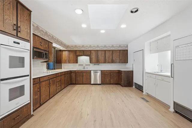 a large white kitchen with stainless steel appliances a sink and cabinets